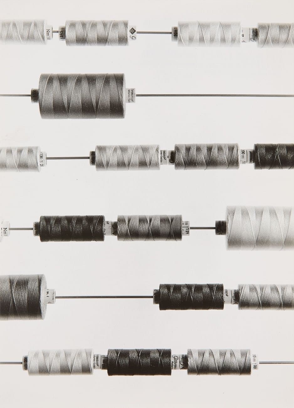 Archival black-and-white photograph of thread spools on horizontal rods
